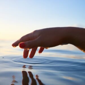 A hand dipping in a body of water.