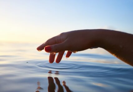 A hand dipping in a body of water.
